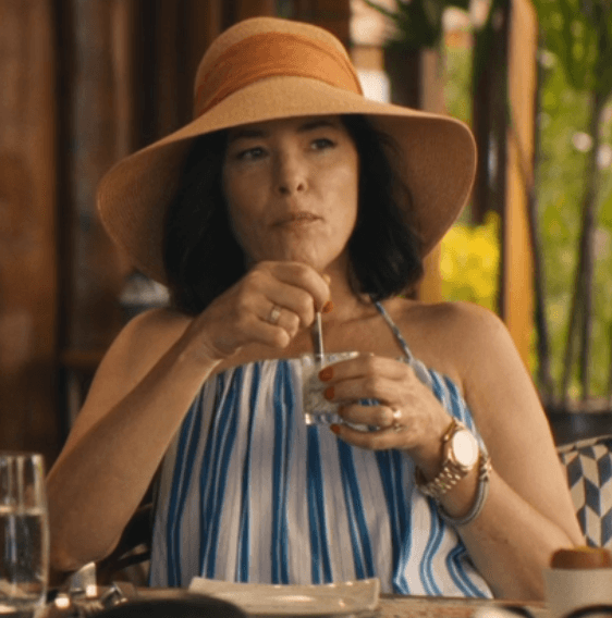 Victoria Ratliff embodies relaxed vacation chic in a vibrant striped strapless top, perfectly complemented by a wide-brimmed straw hat, as she savors a moment of leisure.
