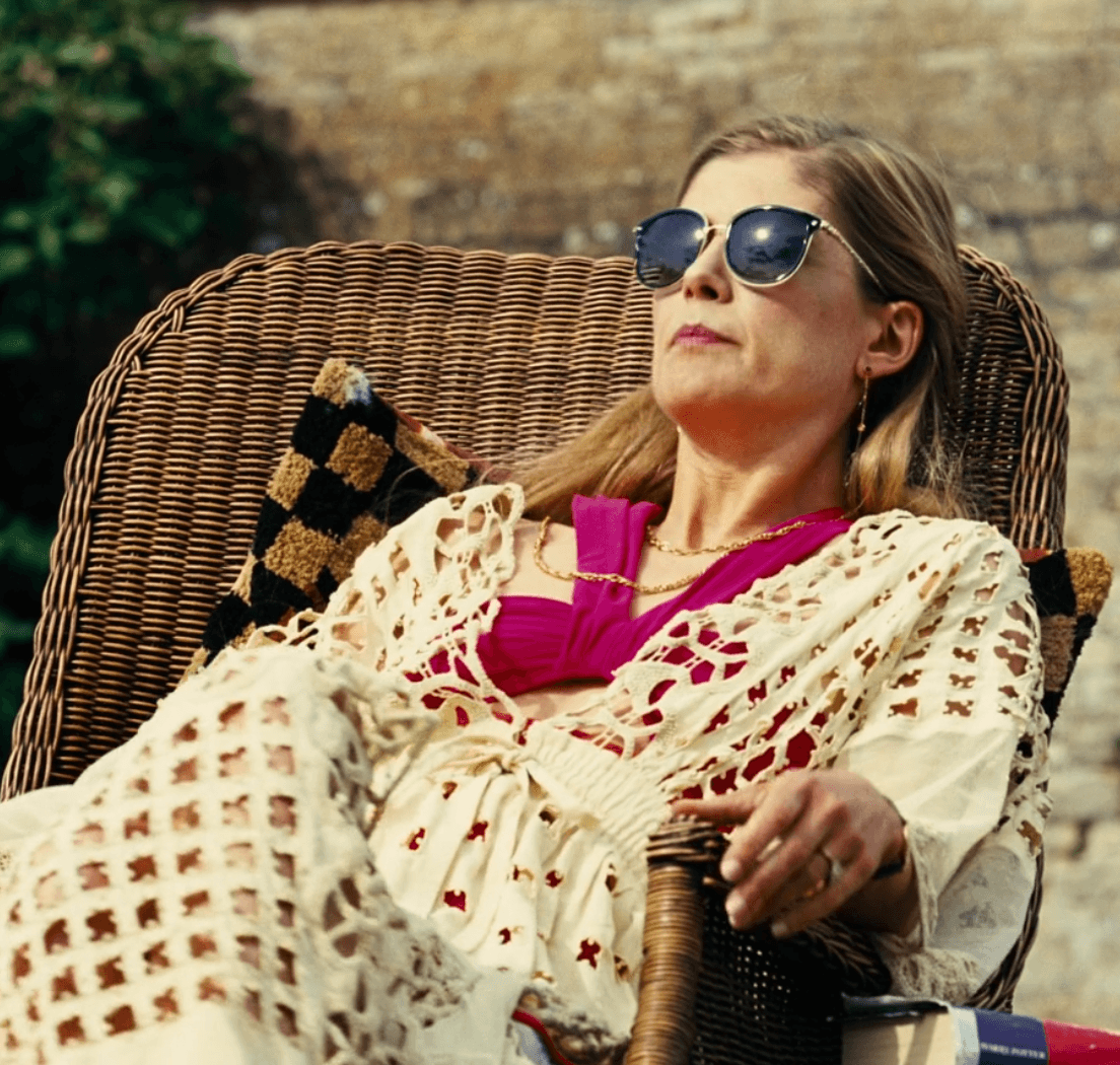 Elspeth embodies effortless poolside glamour, lounging in a vibrant fuchsia bikini top layered with a delicate, open-knit cream cover-up, perfectly accessorized for a sun-drenched afternoon.