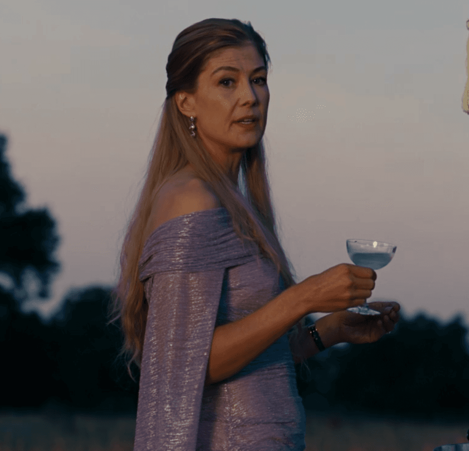Elspeth Catton embodies effortless evening glamour in a shimmering off-the-shoulder gown, its ruched lavender fabric catching the last light of dusk.